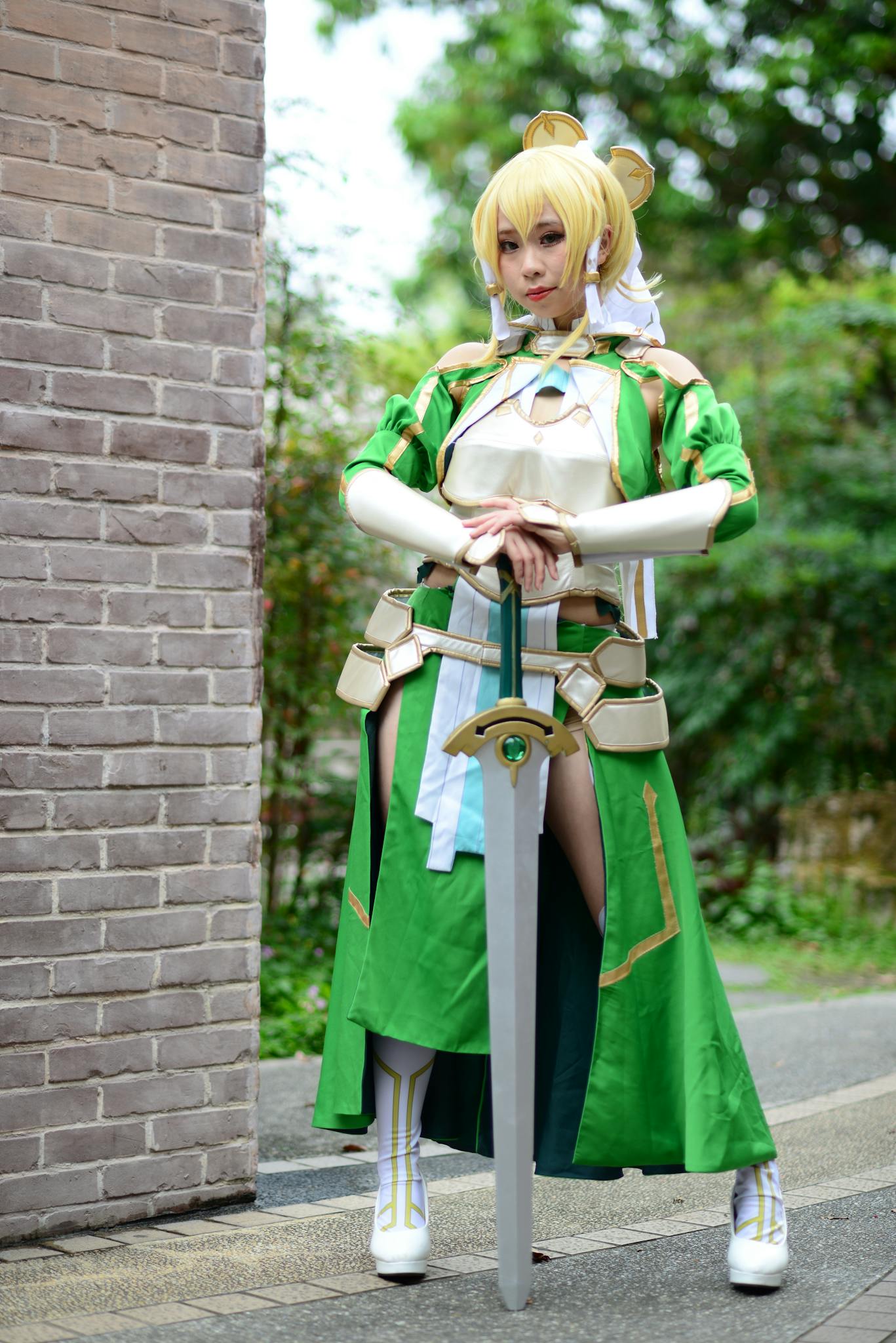 Cosplayer dressed as Leafa from Sword Art Online standing outdoors with a sword. Captivating costume details.